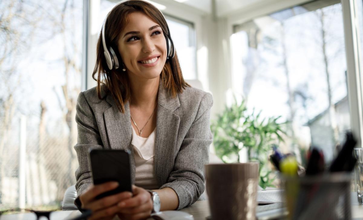 Female business professional providing remote support with her headset and smartphone.