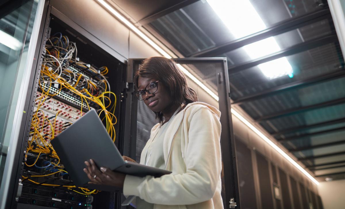 Female IT tech troubleshooting a server in a data center.