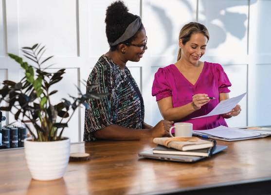 two people standing side by side looking at a piece of paper