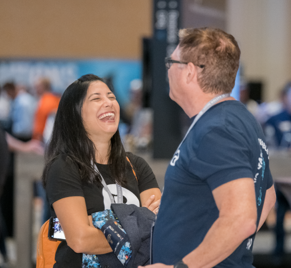 A man and a woman at a conference, talking and laughing