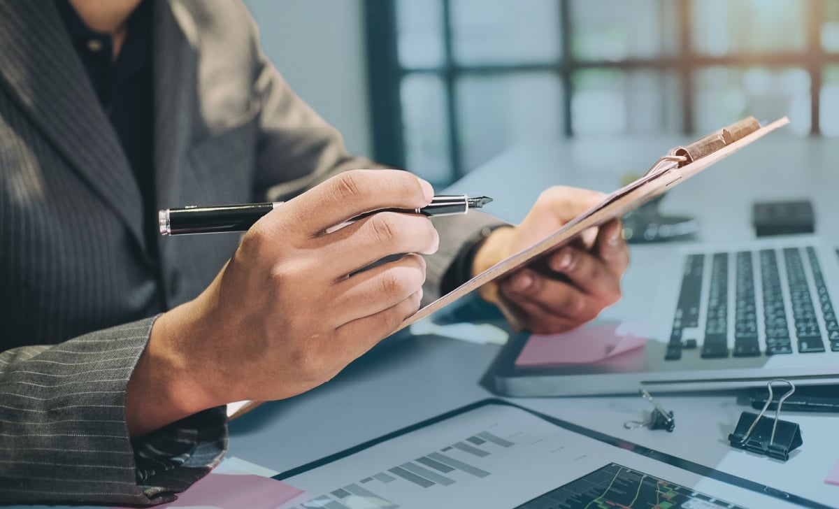 Someone filling out a document on a clipboard at a desk