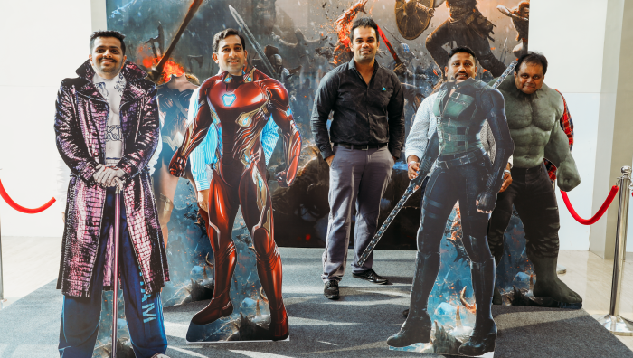 five people posing behind Marvel superhero cutouts