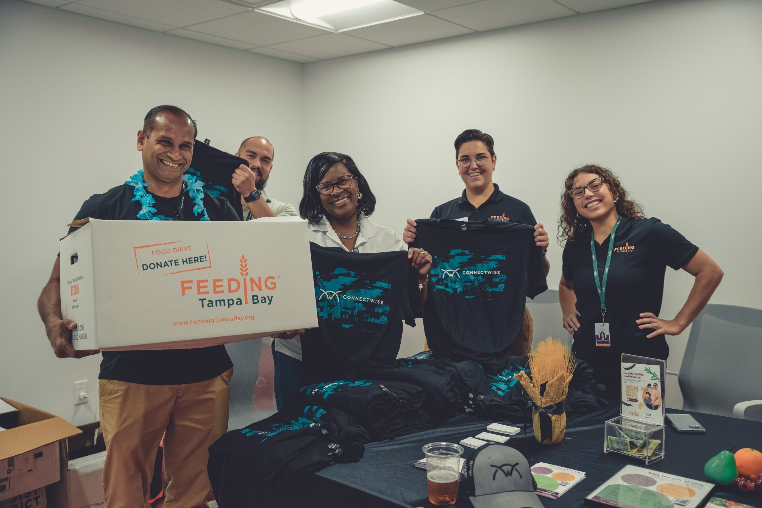 Five people holding up ConnectWise t-shirts