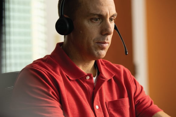 A white man wearing a headset looking serious