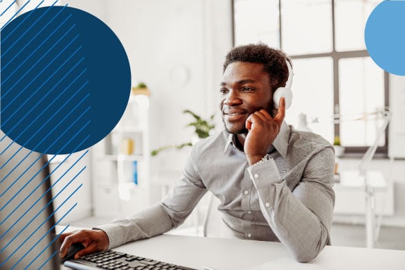 Black man wearing headphones using a computer in a sunny office