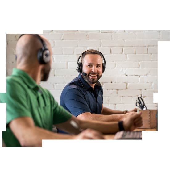Two men wearing headsets talking and smiling